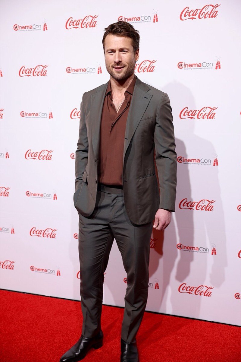 Glen Powell: Grey suit and brown shirt